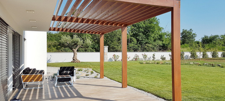 Carport mit Holzdach als Unterstand für ein geparktes Auto.