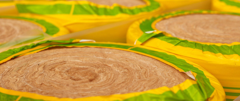Gerollte Dämmwolle in gelb-grüner Verpackung, bereit für den Einsatz in Wärmedämmung und Schallschutz.