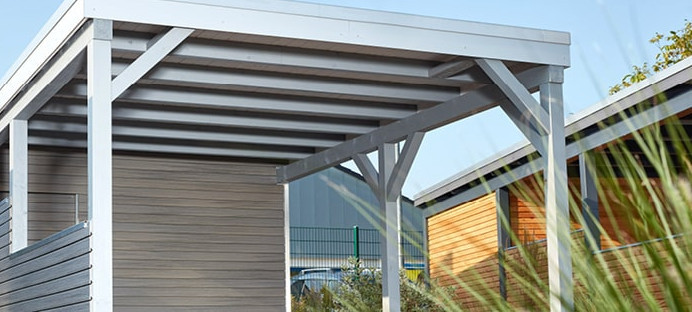 Carport mit Holzdach als Unterstand für ein geparktes Auto.