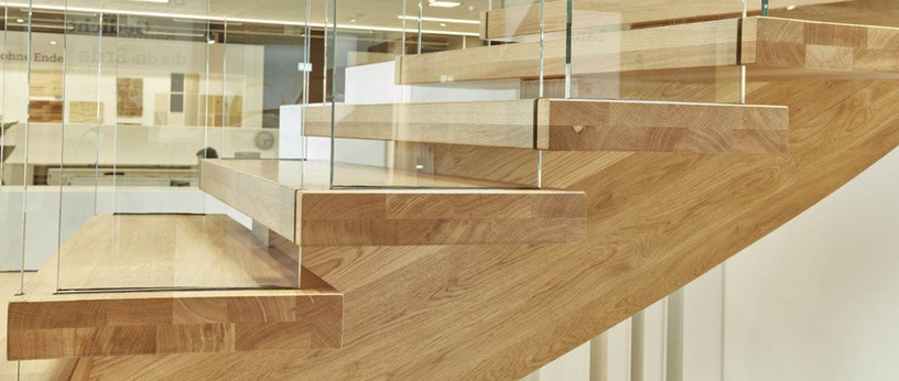 Moderne Holztreppe mit Glasgeländer und massiven Stufen aus Eichenholz in zeitgemäßem Design.