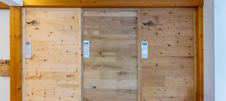 Drei verschiedene Wandpaneele in Holzoptik nebeneinander in der Ausstellung, mit Beschriftungsschildern.