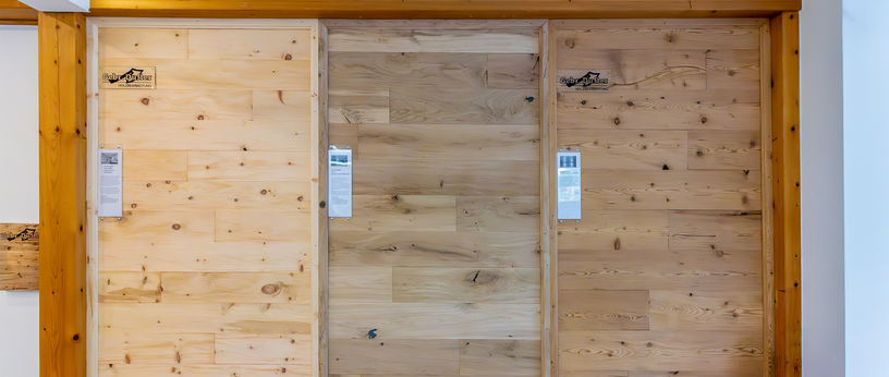 Drei verschiedene Wandpaneele in Holzoptik nebeneinander in der Ausstellung, mit Beschriftungsschildern.