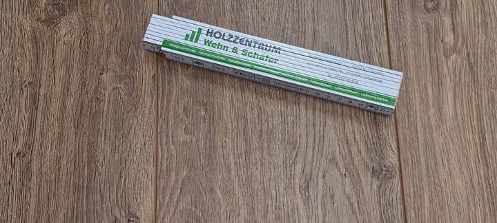 Zollstock mit Firmenlogo Wehn & Schäfer auf Laminatboden.