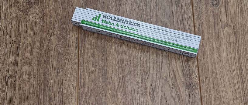 Zollstock mit Firmenlogo Wehn & Schäfer auf Laminatboden.