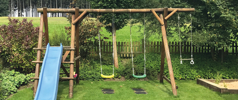 Spielgeräte: Schaukel und Rutsche für Kinder im Garten.
