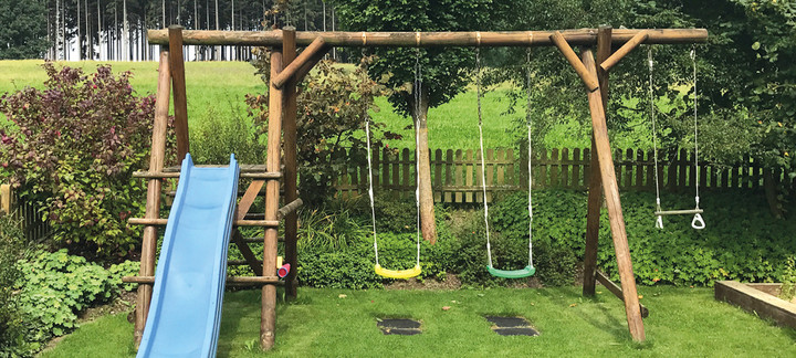 Spielgeräte: Schaukel und Rutsche für Kinder im Garten.